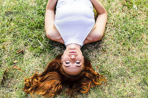 Portrait of redheaded woman lying on a meadow