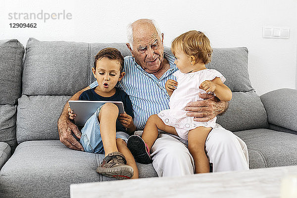 Portrait of grandfather spending time with his grandson and granddaughter at home