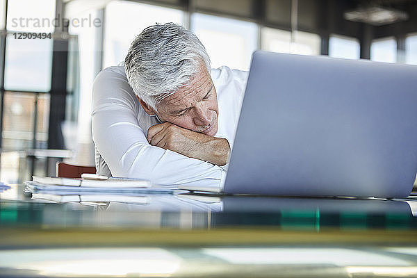 Exhausted businessman sleeping in front of laptop