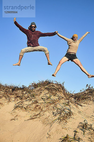 Portugal  Algarve  couple on the beach jumping down dune