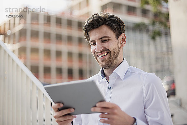 Smiling businessman in the city using tablet