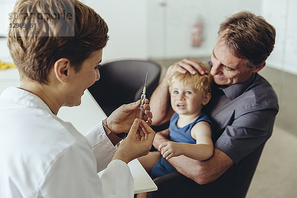 Father holding son while being vaccinated by pedeatrician