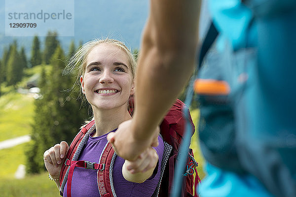 Germany  Bavaria  Brauneck near Lenggries  happy young woman hiking in alpine landscape holding hand of boyfriend