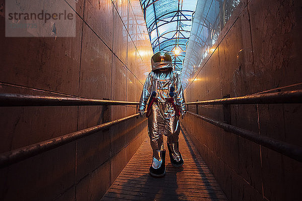 Spaceman in the city at night walking in narrow passageway