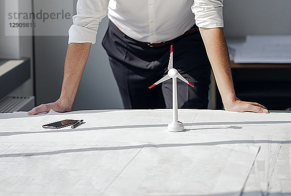 Engineer working in his office with model of a wing´d wheel on his desk
