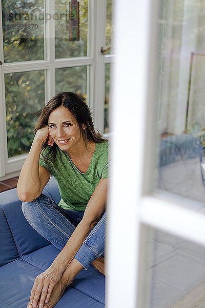 Smiling mature woman sitting on couch at home