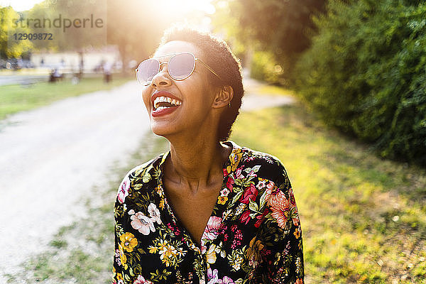 Laughing young woman wearing sunglasses outdoors at sunset