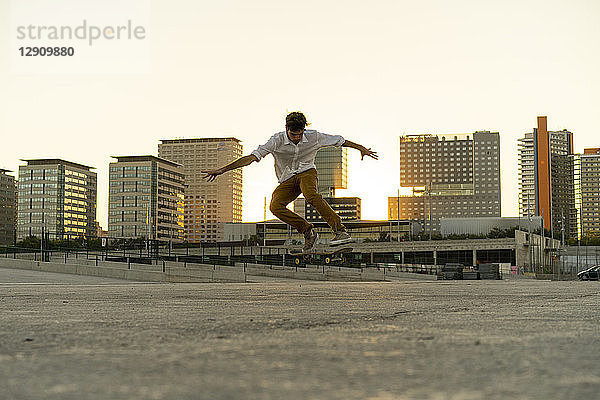 Young man doing a skateboard trick in the city at sunset