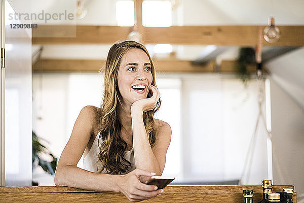 Happy brunette woman with cell phone at home
