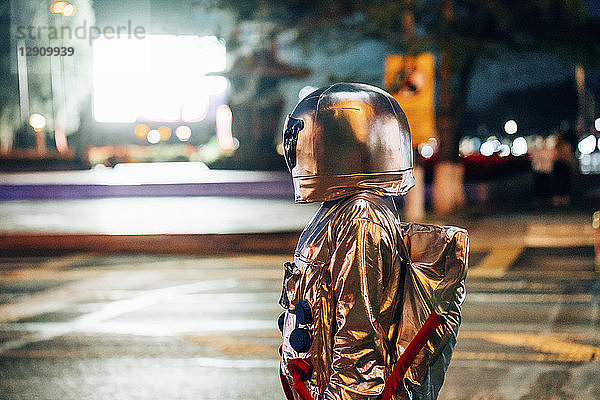 Spaceman on a street in the city at night attracted by shining projection screen