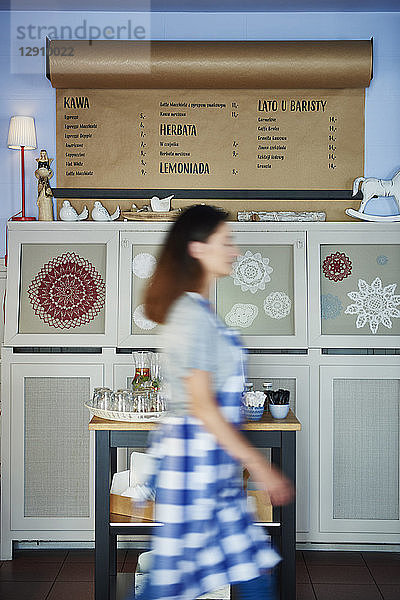 Waitress walking past drinks menu in a cafe