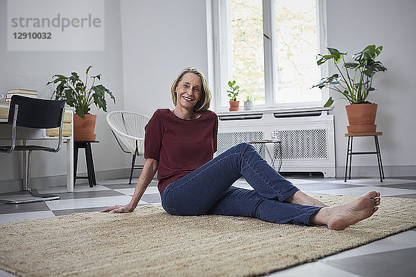Smiling mature woman sitting on the floor at home