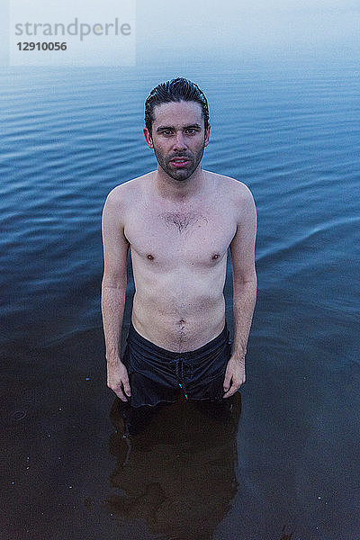 Man with bare chest standing in lake