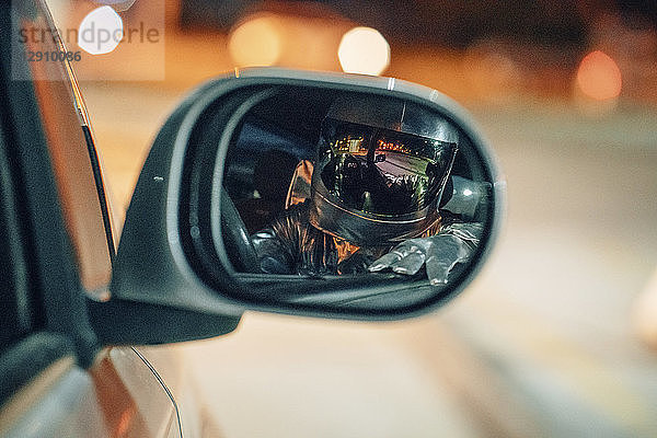 Reflection of spaceman in wing mirror of a car at night