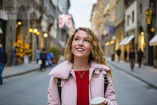 Italy  Florence  portrait of smiling tourist walking with coffee to go on the street in the evening