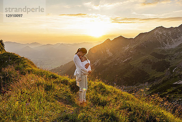 Germany  Bavaria  Oberstdorf  mother holding little daughter on a hike in the mountains at sunset