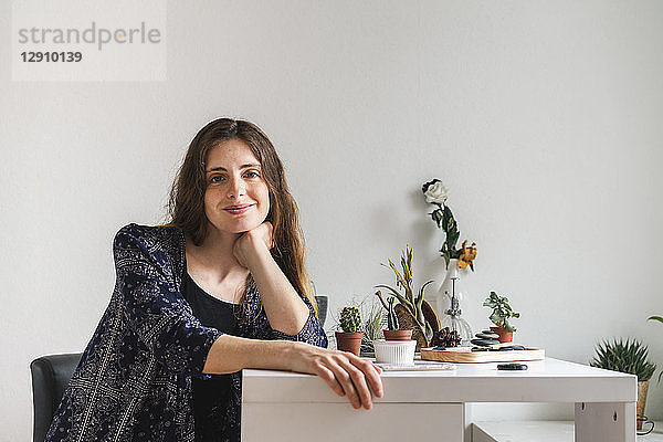 Portrait of smiling young woman at home surrounded by plants