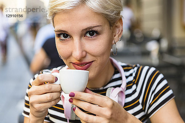 Portrait of smiling young woman drinking espresso at pavement cafe
