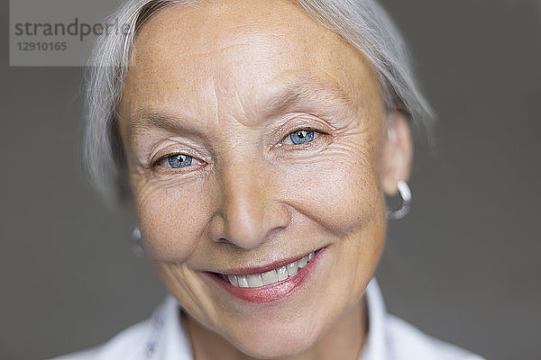 Portrait of smiling senior woman with grey hair and blue eyes