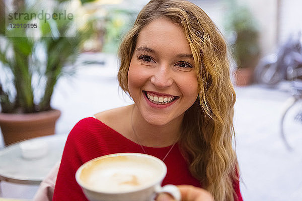 Portrait of laughing young woman with tea cup at pavement cafe