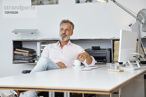 Businessman sitting at desk in office thinking