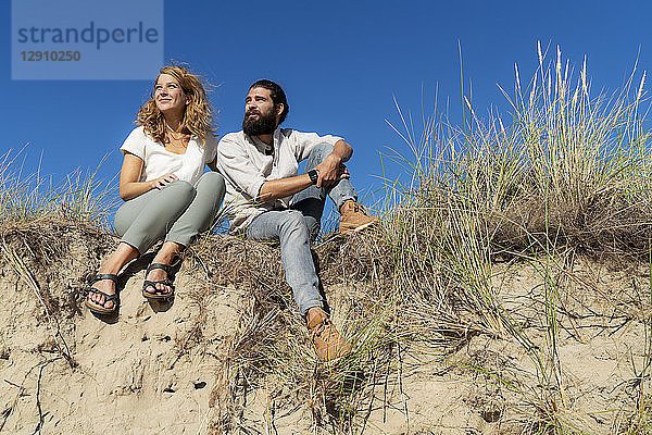 Young couple sitting on a dune in summer  relaxing