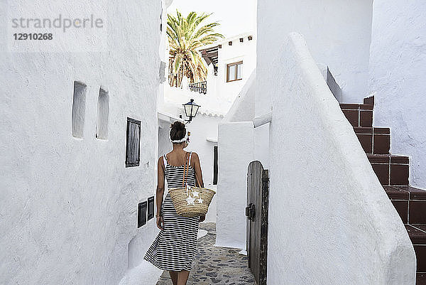 Spain  Menorca  Binibequer  back view of woman walking in an alley