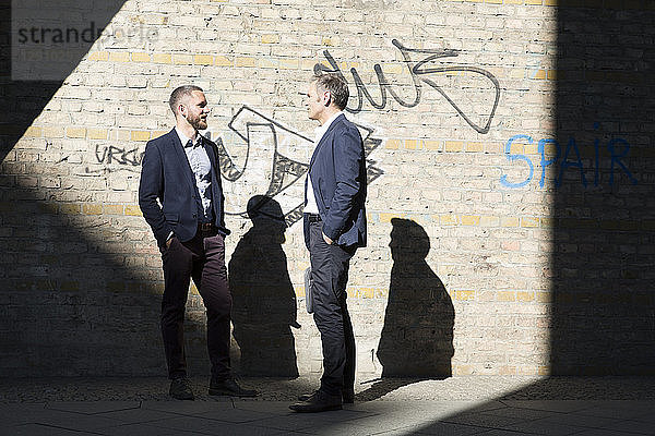 Two businessmen talking at graffiti wall