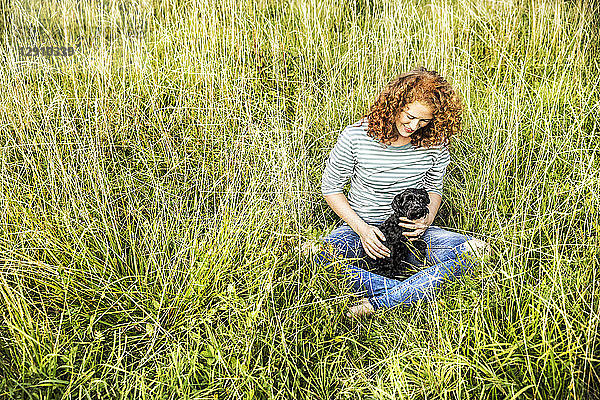 Young woman relaxing on a meadow with her dog