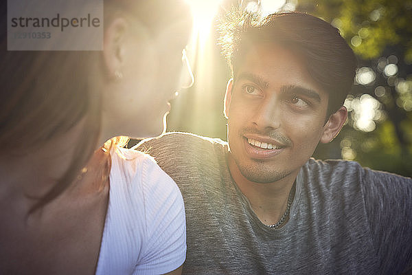 Romantic young couple sitting in park  enjoying sunset