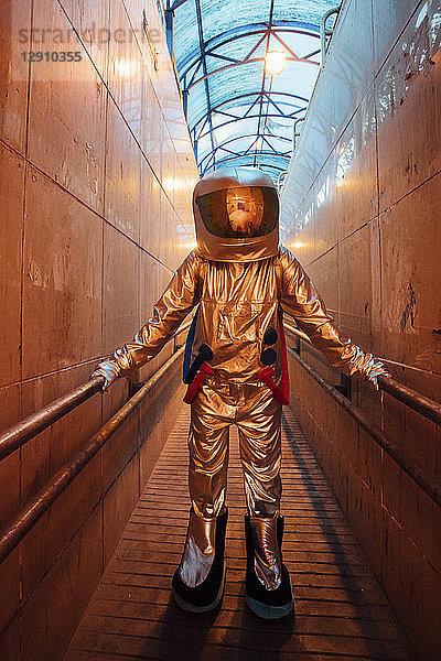 Spaceman in the city at night standing in narrow passageway