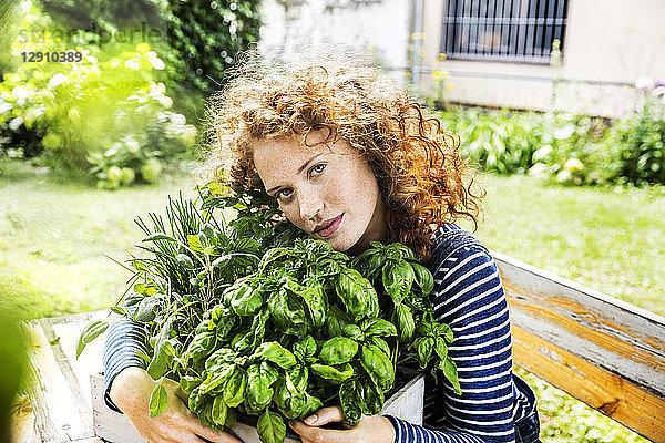 Portrait of young woman with fresh herbs in a box