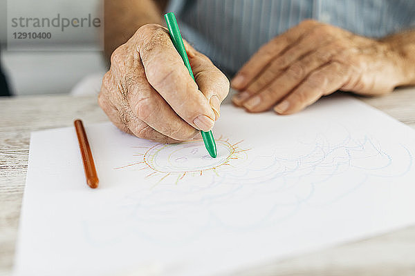 Senior man's hand drawing with green pencil  close-up