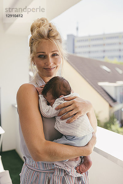 Portrait of smiling mother holding her baby on balcony