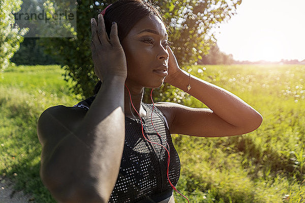Young athlete in nature  listening music with headphones  preparing for training