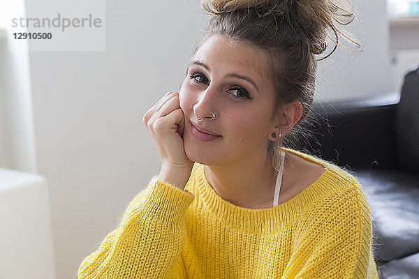 Portrait of smiling young woman with nose piercing wearing yellow pullover
