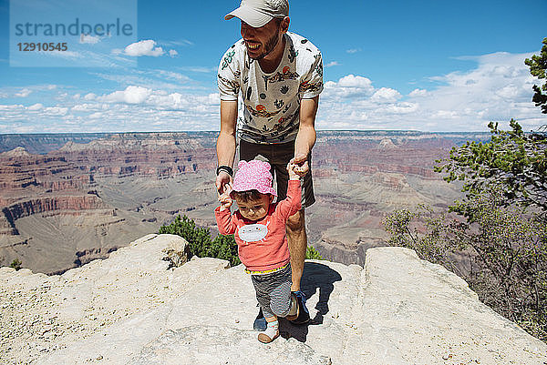 USA  Arizona  Grand Canyon National Park  father and baby girl on viewpoint  girl learning to walk