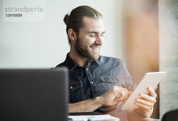 Smiling businessman using tablet at desk in office