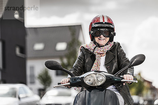 Active senior lady riding motor scooter in the city