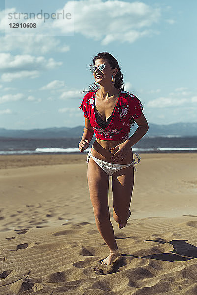 Portrait of laughing teenage girl running on the beach