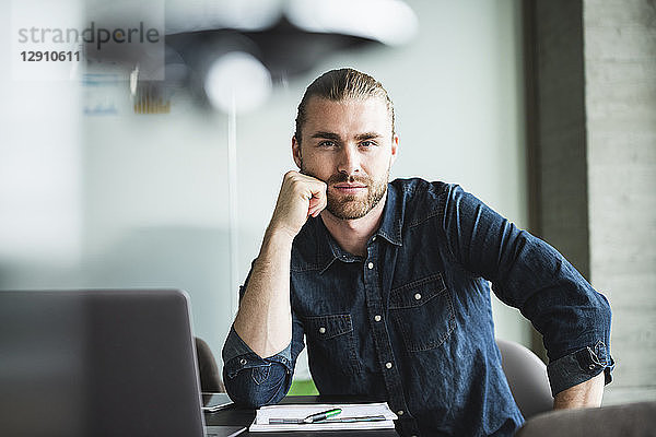 Portrait of confident casual businessman at desk in office