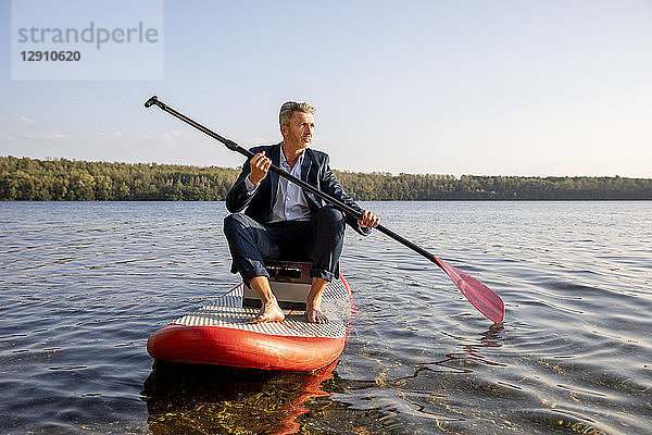 Businessman paddling on lake