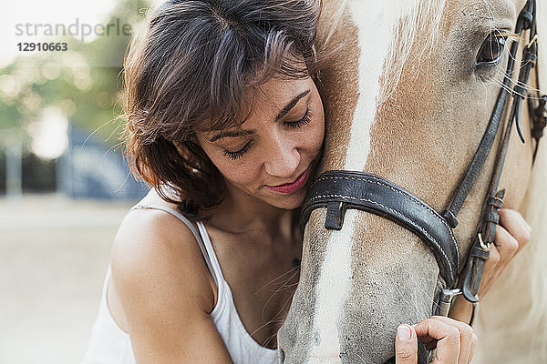 Woman cuddling riding horse