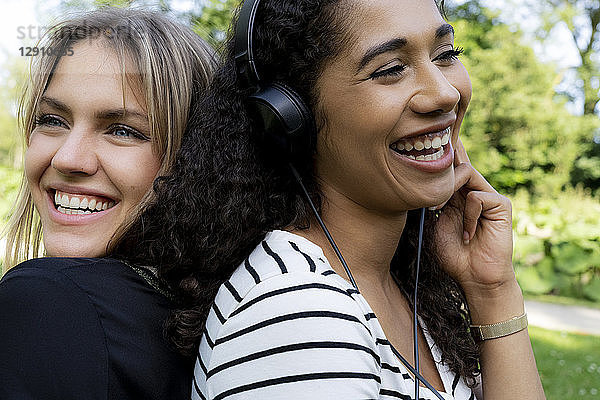Two girlfriends in a park listening music  laughing  having fun