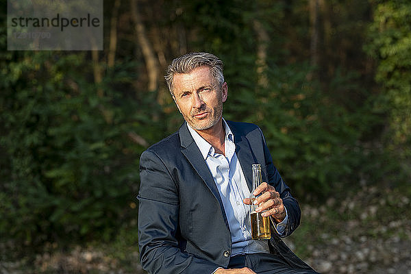 Portrait of businessman with beverage in nature