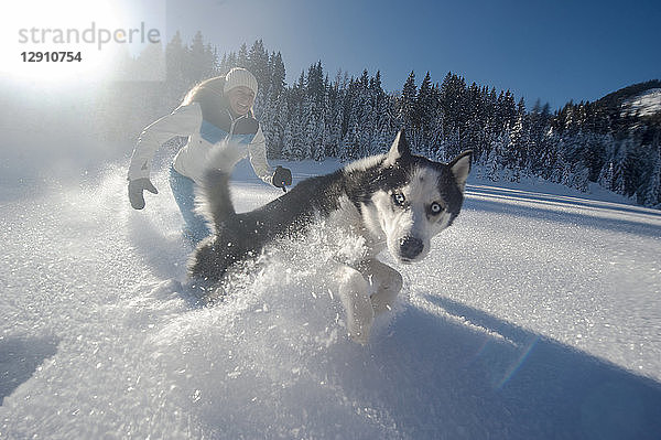 Austria  Altenmarkt-Zauchensee  happy young woman running with dog in snow