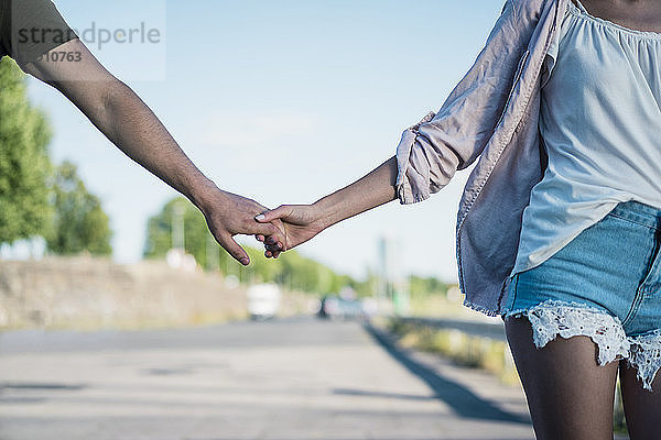 Close-up of couple hand in hand on waterfront promenade