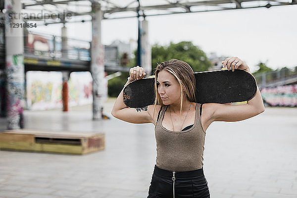 Cool young woman carrying skateboard in the city