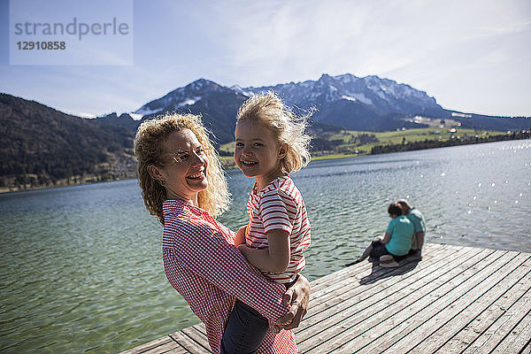 Austria  Tyrol  Walchsee  happy mother carrying daughter at the lake