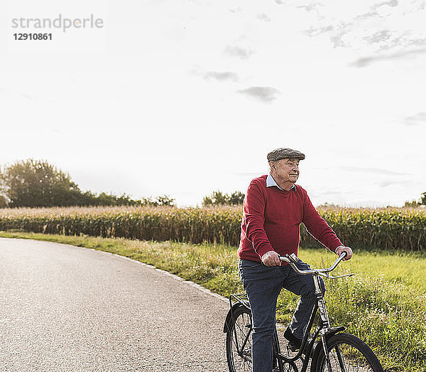 Senior man riding bicycle on country lane
